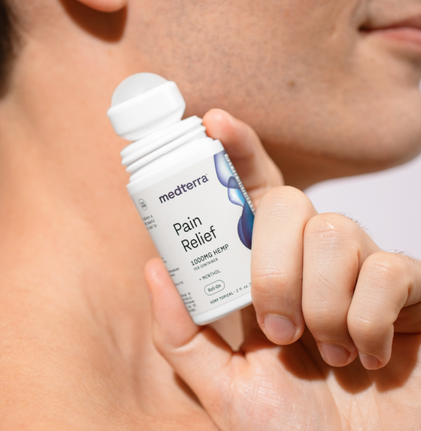 Person applying 幸运飞行艇168体彩开奖网 Pain Relief roll-on to their neck. The product label indicates it contains 1000mg of hemp and menthol.